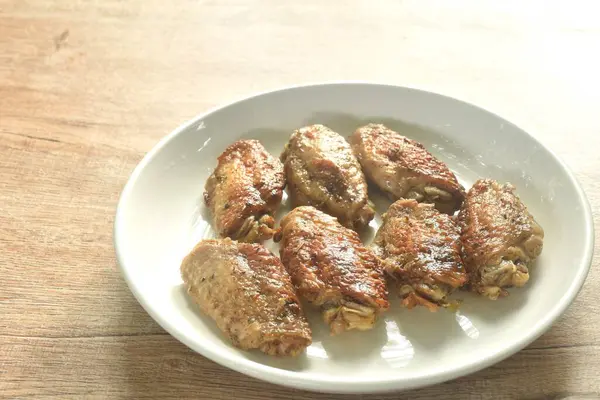 Izgara tuzlu ve baharatlı tavuk kanadı ve tabağında karabiber.