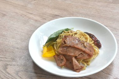 Kızarmış spagetti üzerine kızarmış domuz pastırması ve tabakta dolmalık biberli kuru kırmızı biber.   