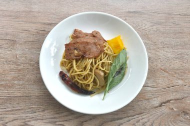 Kızarmış spagetti üzerine kızarmış domuz pastırması ve tabakta dolmalık biberli kuru kırmızı biber.   