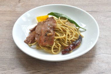 Kızarmış spagetti üzerine kızarmış domuz pastırması ve tabakta dolmalık biberli kuru kırmızı biber.   