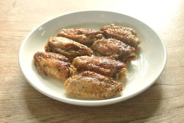Izgara tuzlu ve baharatlı tavuk kanadı ve tabağında karabiber.