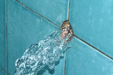 Kırık tesisattan su sıçrıyor. Banyodaki mavi politen boru hattı.