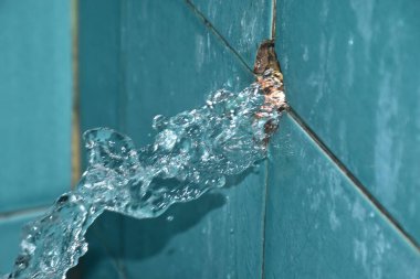 Kırık tesisattan su sıçrıyor. Banyodaki mavi politen boru hattı.