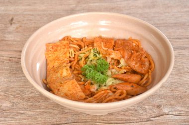 Japon eriştesini dilimlenmiş domuz sosisiyle karıştırın ve Kore kimchi soslu lahana tofusu.