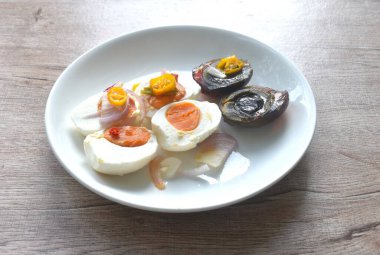 Haşlanmış tuzlu ve siyah yumurta yarısı dilimlenmiş arpacık soğanı ve acı biberli salata.