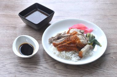 Dilimlenmiş ördek çifti çıtır çıtır domuz üstü pilav pembe turşulu zencefil ve haşlanmış lahana soslu tatlı soya sosu tabakta. 