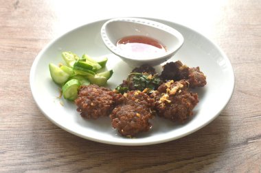 Kızarmış tuzlu pirzola, sarımsaklı, acı biber soslu ve tabakta salatalık dilimlenmiş domuz eti.