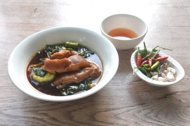 Kızarmış domuz budu yahnisi siyah Çin sebze çorbası ve lahana sosu karışık baharatlı acı biber sosu tabakta birkaç tane taze sarımsak yiyin.