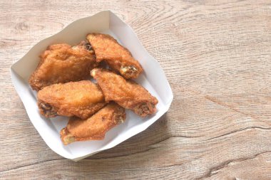 Kızarmış tuzlu tavuk kanadı. Masaya konmuş papay tepsisiyle düzenleniyor.