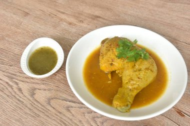 Tavuğu sert pişirmek ve bacağını tabakta otla daldırmak baharatlı ve acı biber sosunu fincana karıştırmak.