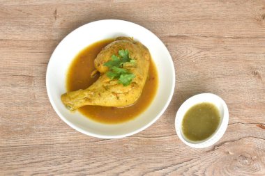 Tavuğu sert pişirmek ve bacağını tabakta otla daldırmak baharatlı ve acı biber sosunu fincana karıştırmak.