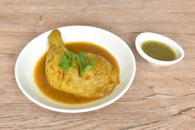 Tavuğu sert pişirmek ve bacağını tabakta otla daldırmak baharatlı ve acı biber sosunu fincana karıştırmak.