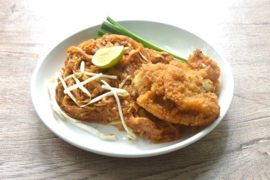 Pad Thai karıştırılmış kızarmış pirinç eriştesi ile karides ve yumurta soslu kızarmış tavuk tabağı. 