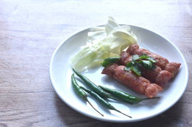 Tayland usulü kızarmış sosis mayalanmış domuz pirzolası ve pilav. Tabakta kırmızı biberli taze lahana.