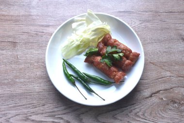 Tayland usulü kızarmış sosis mayalanmış domuz pirzolası ve pilav. Tabakta kırmızı biberli taze lahana.