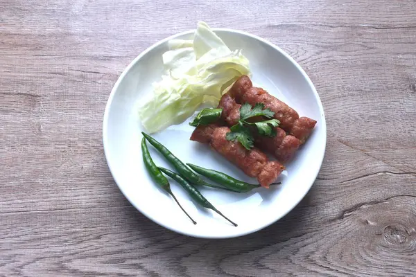 Tayland usulü kızarmış sosis mayalanmış domuz pirzolası ve pilav. Tabakta kırmızı biberli taze lahana.