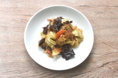 Siyah mantarlı kızarmış cam şehriye ve tabakta siyah soya soslu lahana.