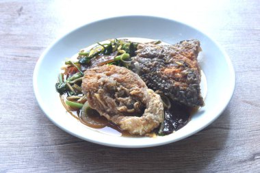 spicy deep fried chop Nile Tilapia or mango fish slice ginger and ear mushroom couple celery dressing soy sauce on plate 