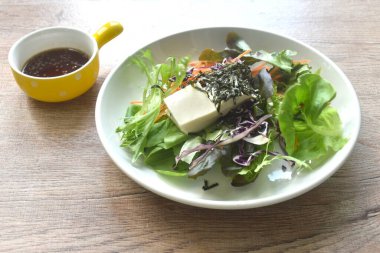 Japon usulü kızarmış susam soslu sebze soslu beyaz tofu tabakta salata.