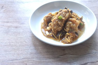 spicy deep fried chop Nile Tilapia or mango fish slice ginger and ear mushroom couple celery dressing soy sauce on plate 