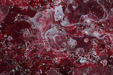 Spilled red and white paint on liquid thinner to form an abstract pattern.