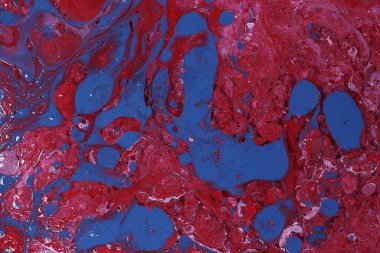 Spilled red, blue and white paint on the thinner solution. Selective focus on pink background.