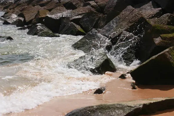 Klippen bir einem wunderschnen Sandstrand. Hier berschwemmt das Wasser die Steine von den Klippen.