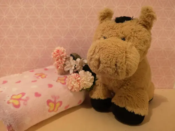 Kuschelpferd, das neben Bluemchen steht. Ein wunderschoenes Motiv fr ein Kinderzimmer oder fr Babyfotografie.