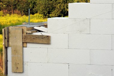 İnşaat pimi, güçlendirilmiş beton kiriş, çelik parmaklıklar ve inşaat halindeki bir evin birinci katında ahşap bir yapı, otoklamalı betondan yapılmış duvarlar.