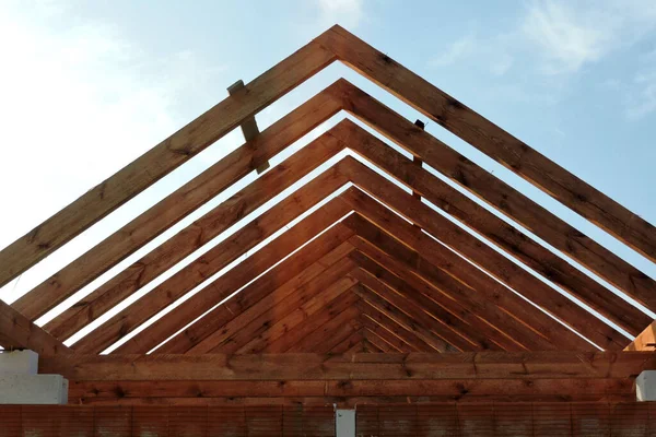 A timber roof truss of a house under construction, reinforced brick lintels, blue sky in the background