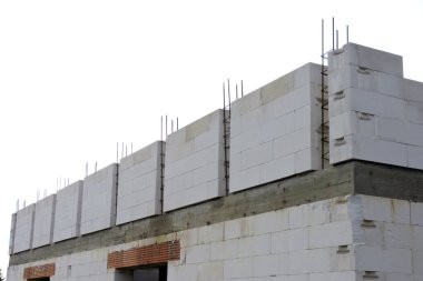 A reinforced concrete beam, steel reinforcement for pillars on the first floor of a house under construction, a reinforced brick lintel, a rough window opening , walls made of aac