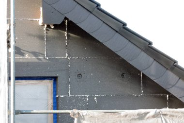 Termal yalıtım için EPS grafit polistiren panolarla kaplı bir ev duvarı koruyucu bir filmle kaplı bir pencere, bir iskele...