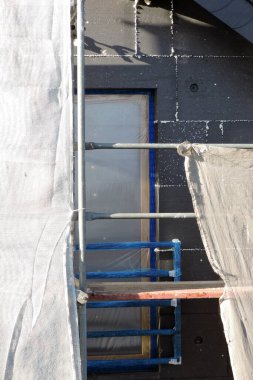 Termal yalıtım için EPS grafit polistiren panolarla kaplı bir ev duvarı koruyucu bir filmle kaplı bir pencere, bir iskele...