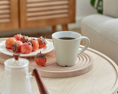 Tahta tepside taze hurmalarla sıcak sabah kahvesi