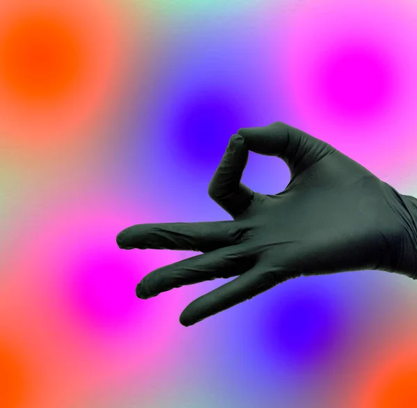 在彩色背景上戴着黑色手套的手的符号 — 图库照片