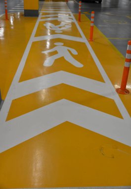 Şehirdeki alışveriş merkezinin yeraltı garajındaki yayalar ve arabalar için trafik işaretleri
