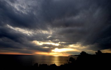 Açık denizde gün batımı, bulutlu gökyüzü