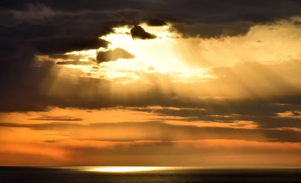 落日笼罩在开阔的海面之上 天空乌云密布 图库图片