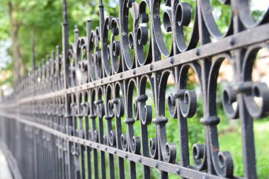 Arkasında parkı olan demirden yapılmış eski bir çit.