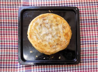 Ekose masa örtüsünün üzerinde, yemek tepsisinde pişmiş turta.