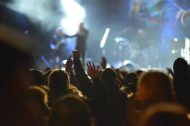 Rock konserinde sahnenin önünde çalan insanların kafaları ve elleri.