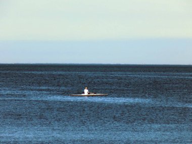 Denizin ortasındaki kayıkta yalnız bir adam.
