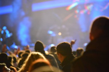 Rock konserinde sahnenin önünde çalan insanların kafaları ve elleri.