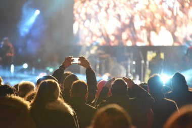 Rock konseri sırasında sahneyi cep telefonuyla kaydeden insanların kafaları ve elleri.