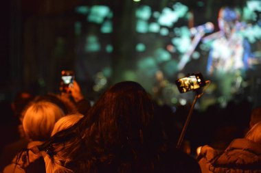 Rock konseri sırasında sahneyi cep telefonuyla kaydeden insanların kafaları ve elleri.