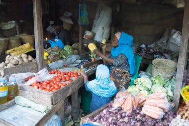 Mtowambu, Tanzanya - 12 Ekim 2022: Kızı izlerken bir ananas soyan bir pazar satıcısı.