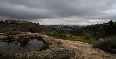 An ancient manmade waterhole, filled with rainwater on a hill next to Jerusalem, Israel, on a cloudy winter morning.