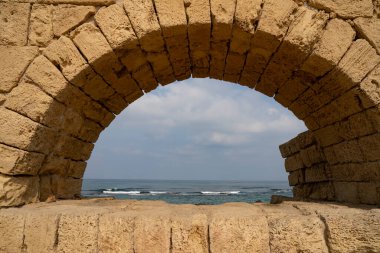 Akdeniz, açık ve güneşli bir günde, Caesarea, İsrail, sahildeki antik Roma su kemerinin kemerinden görüldüğü gibi..