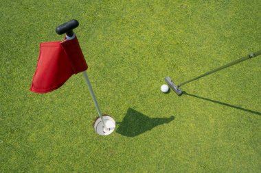 Golf sopası, kırmızı bayrakla işaretlenmiş golf topunu deliğe sokmak için kullanılır..