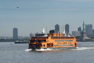 New York, ABD - 21 Temmuz 2023: Staten Island feribotu, bulutlu bir günde New York körfezinde özgürlük heykelinin yanından geçtikten sonra.